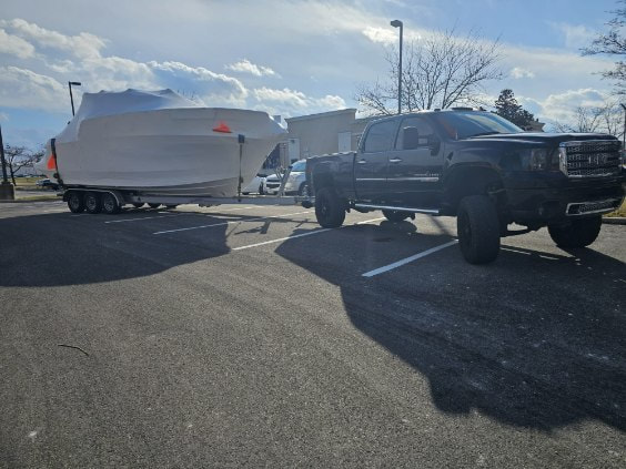 GMC pulling a wrapped boat on a trailer as power only load. 