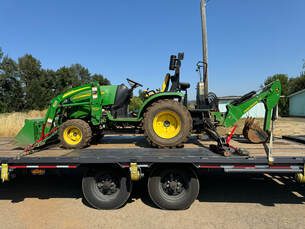 Gooseneck trailer loaded with tractor and materials.