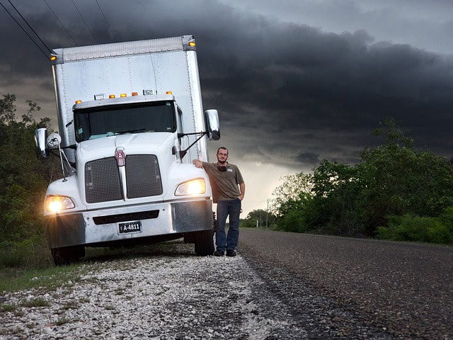 Semi truck with setting sun and snow on the ground.